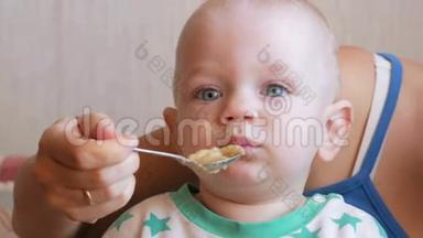 妈妈用勺子喂美丽的婴儿吃<strong>水果粥</strong>。 孩子仔细看了一点。 特写